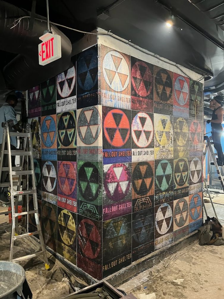 Fallout shelter wheat paste posters as backdrop for graffiti artist