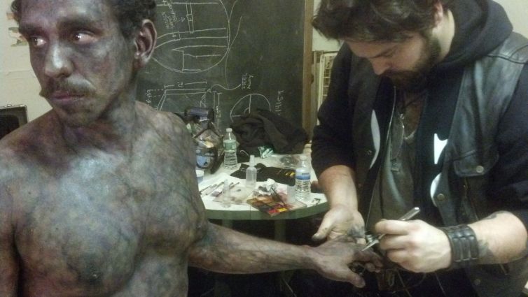 Director Tate Steinsiek does final looks on actor Ray Santiago's corpse makeup