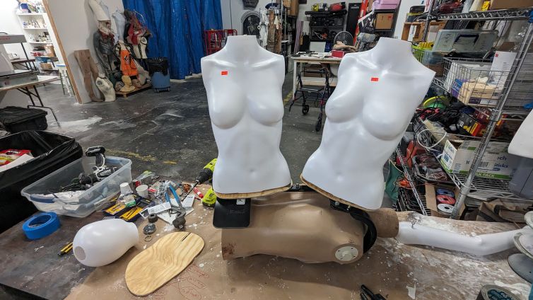 Initial mannequin backpack attachment of two blank torsos with wooden bases on musician backpack frame for Death Becomes Her the Broadway musical