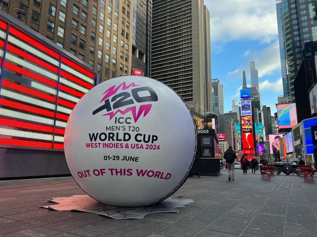 Giant cricket ball promotion in Times Square in NYC in front of neon American flag